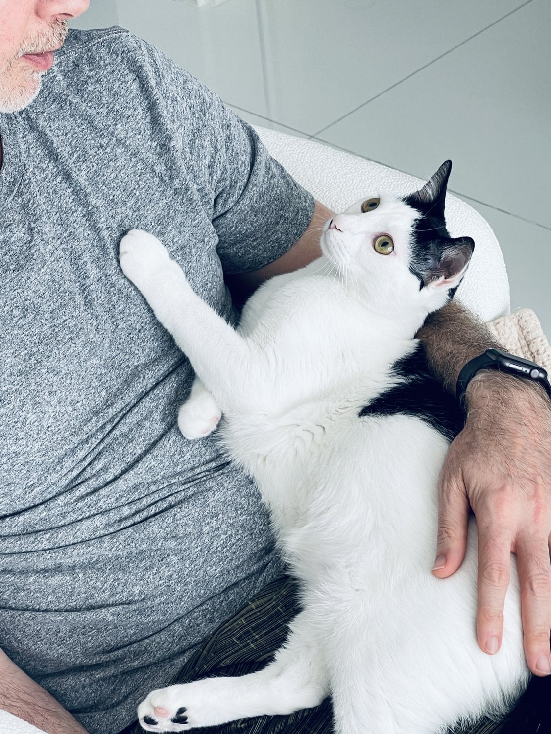 Cory cuddling Louis, the black-and-white cat, belly-up on his lap