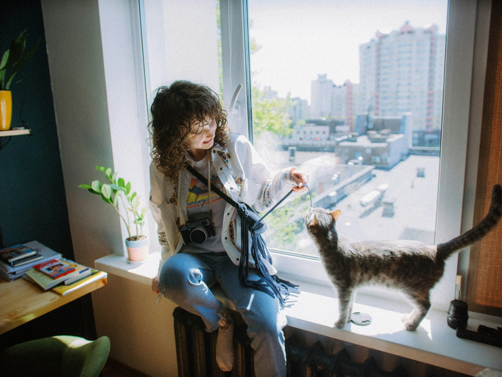 A woman on a windowsill talking to her cat, who is looking up at her